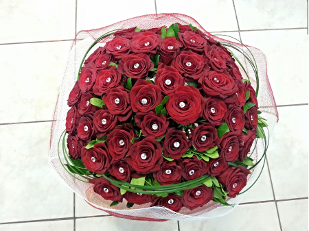 Bouquet of flowers with red roses and grasses in a spherical shape.